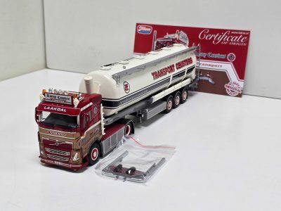 Scale model: red Volvo truck pulling a white tanker trailer labeled TRANSPORT GEUSTERS on a white surface, with small accessory parts in bags nearby.