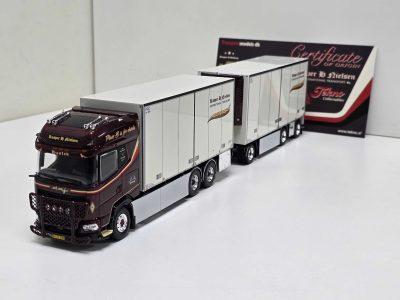 Scale model of a dark red truck with a row of white refrigerated trailers in a showroom, with a large 'Certificate of Origin' display in the background.