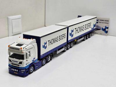 Scale-model white Scania truck with blue-trimmed trailers branded 'THOMAS BOERS' on a white studio surface.