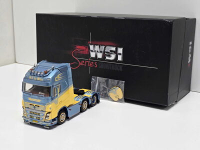 Blue and yellow toy Volvo truck in the foreground with a large black box reading 'WSI Series Showtruck' behind it.