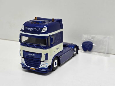 Blue and white toy DAF truck on a white surface, displaying the 'Wisgerhof' branding on the cab.