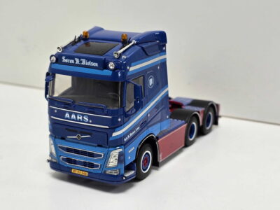 Blue toy truck with white stripes and orange beacon lights, front view showing 'Søren H. Nielsen' lettering on the cab.