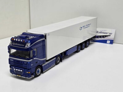 Blue toy truck with a long white trailer indoors; side shows 'Slimers Transport' logo in blue/gray.