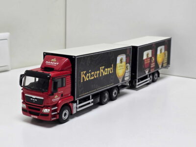 Red toy truck with a long black trailer advertising BeizerKarel beer on a white surface.