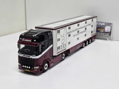 Scale model of a red and white Scania semi-truck with a long white trailer, parked on a white surface; the trailer features German text and logos such as EVERS and other markings.
