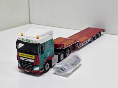 20260523_162903 - Degen Miniaturen Toy model semi-truck with a green cab and red trailer on a white surface, showing the truck and trailer.
