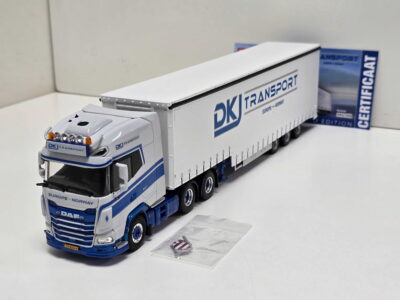 20260523_163353 - Degen Miniaturen Scale model of a white and blue DK Transport DAF truck with a long trailer on a white surface, with papers nearby.