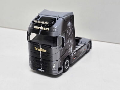 Close-up of a black toy truck with a 'The Godfather' label on the front bumper and a small license plate row beneath the grille.