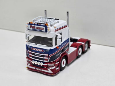Scale-model Scania toy truck in red, white, and blue with a cargo trailer on a white background