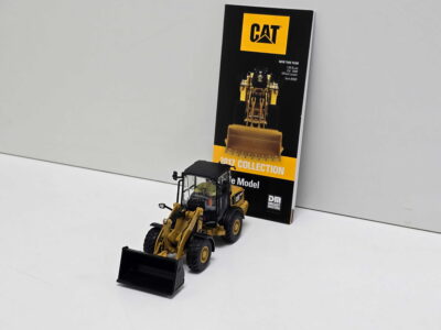 20260819_133154 - Degen Miniaturen Yellow CAT construction vehicle model in front of a black CAT brochure with a yellow logo