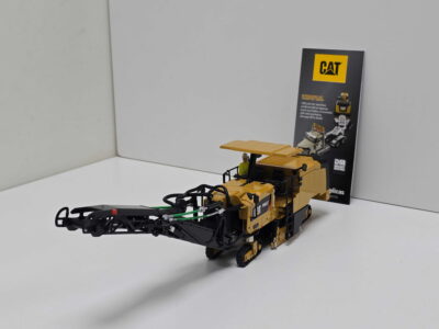 20260819_133451 - Degen Miniaturen Yellow CAT excavator model on a white surface with a brochure standing behind it.