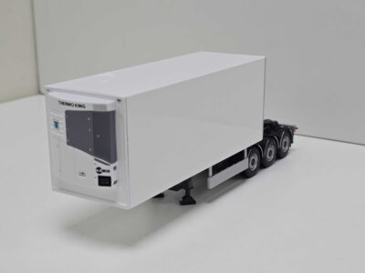 White Thermo King refrigerated trailer unit mounted on a wheeled trailer in a plain room, viewed from the side front corner.