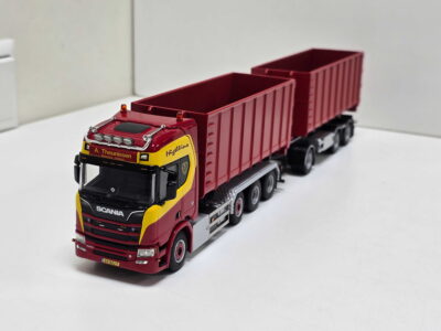 Red Scania toy truck with two red cargo trailers on a white surface (scale model).]} }? Wait format must be proper JSON. Let's craft correctly.