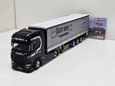 Scale model of a black Scania tractor with a long gray Datrans Nederland trailer on a white surface.