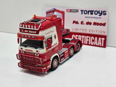 Red Scania toy truck with chrome detailing and multiple headlights, shown up close with a white and red cab, and a Tontoys box in the background.
