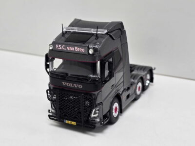 Black die-cast Volvo truck model with 'F.S.C. van Bree' on the cab, yellow Dutch license plate 83-BKJ-4, shown on a white surface.